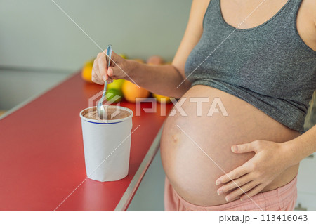 Happy pregnant young woman eating ice cream Happy pregnant young woman eating ice cream 113416043