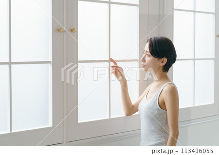 窓の外を不思議そうに見る30代女性 113416055