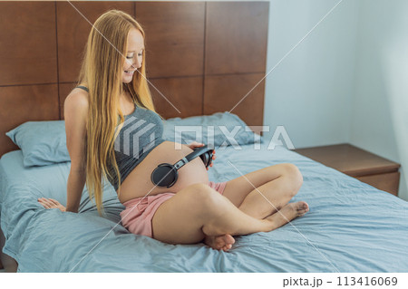 Expectant mom finds joy in her pregnancy, listening to soothing music for a serene and harmonious connection with her unborn baby 113416069