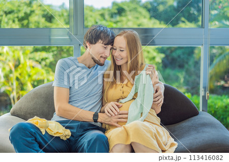 In a heartwarming scene, the future mom and dad hold their unborn baby's clothes in their hands, savoring the joy of anticipation and shared excitement for their little one's arrival In a heartwarming scene, the future mom and dad hold their unborn baby's clothes in their hands, savoring the joy of anticipation and shared excitement for their little one's arrival 113416082