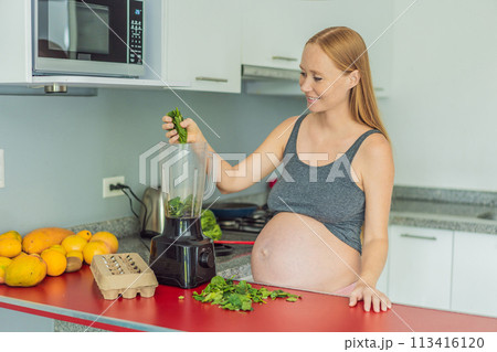 Embracing a nutritious choice, a pregnant woman joyfully prepares a vibrant vegetable smoothie, prioritizing wholesome ingredients for optimal well-being during her maternity journey 113416120