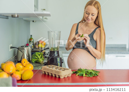 Embracing a nutritious choice, a pregnant woman joyfully prepares a vibrant vegetable smoothie, prioritizing wholesome ingredients for optimal well-being during her maternity journey Embracing a nutritious choice, a pregnant woman joyfully prepares a vibrant vegetable smoothie, prioritizing wholesome ingredients for optimal well-being during her maternity journey 113416211