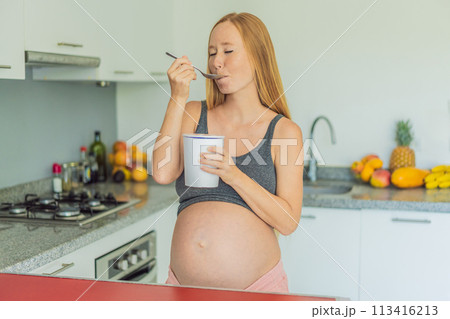 Happy pregnant young woman eating ice cream Happy pregnant young woman eating ice cream 113416213