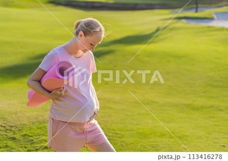 Energetic pregnant woman takes her workout outdoors, using an exercise mat for a refreshing and health-conscious outdoor exercise session Energetic pregnant woman takes her workout outdoors, using an exercise mat for a refreshing and health-conscious outdoor exercise session 113416278