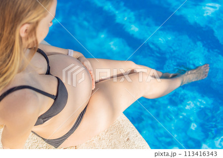 Radiant and relaxed, a pregnant woman finds serenity while enjoying the refreshing embrace of the pool, embracing moments of buoyant joy during pregnancy 113416343