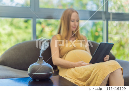 Expectant woman creates a serene atmosphere at home, enjoying the soothing scents of an aroma diffuser during pregnancy 113416399
