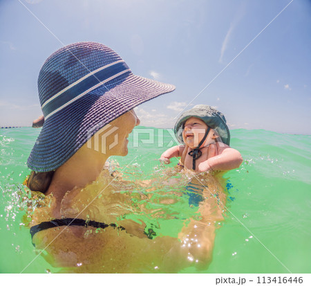 Mother and newborn son share a serene swim in the sea, creating timeless memories by the water's embrace 113416446