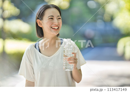 ペットボトルの水を飲むスポーツウエアの若い女性 113417149