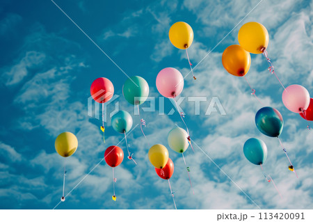 Bunch of colorful helium balloons are floating in blue sky 113420091
