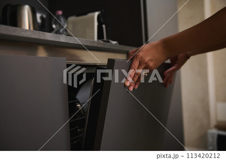 Close-up view, Hand of a woman using a modern dishwasher in the kitchen, closing the door of automatic dishwasher. Housekeeping. Household chores. People and domestic life routine 113420212