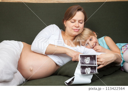 Expectant Mother and Daughter Looking at Ultrasound 113422564