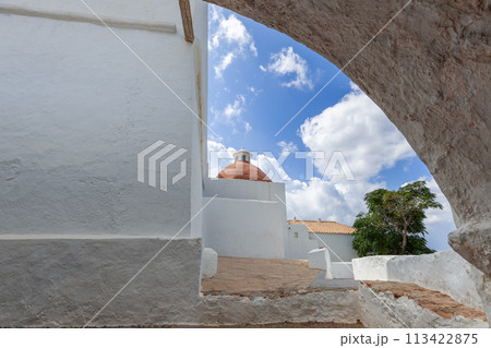 Old stone arch framing the terracotta dome of Puig de Missa church in Ibiza 113422875