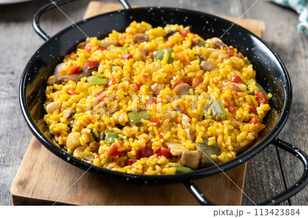Yellow rice with chicken and vegetables on wooden table Yellow rice with chicken and vegetables on wooden table 113423884