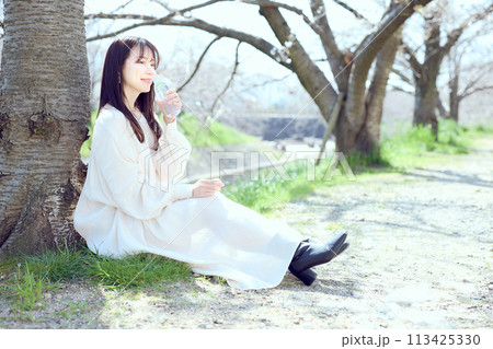 桜の下で水を飲む女性 113425330