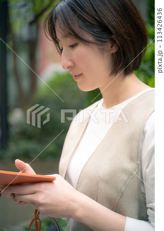 東京丸の内のお店をスマホで探す女性 113426436