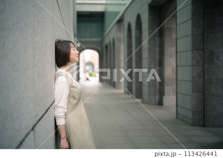 壁に寄りかかる女性 113426441