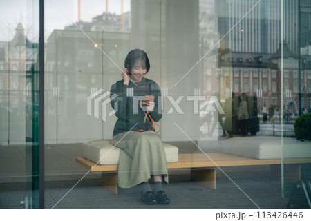 東京駅前の丸の内の街並みを散歩する女性 113426446