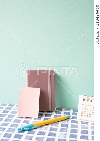 Diary note, pen, and calendar on blue tile desk. mint wall background. workspace 113426460