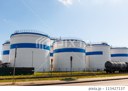 Row many large industrial fuel storage white tanks clear blue sky background on sunny day. Oil storage refinery depot liquid facilities. Energy hazmat railroad transportation storage and distribution Row many large industrial fuel storage white tanks clear blue sky background on sunny day. Oil storage refinery depot liquid facilities. Energy hazmat railroad transportation storage and distribution 113427137