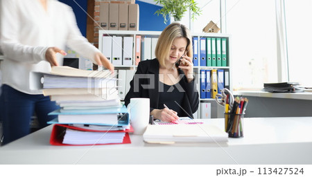 Businessman talking on phone secretary taking documents in office 113427524