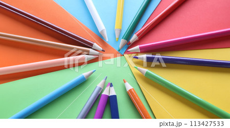 Multi-colored pencils on colored paper on table Multi-colored pencils on colored paper on table 113427533