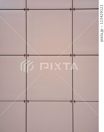 Texture, pattern, background of square panels of orange-pink coral-salmon color, frontally mounted on the wall 113429121
