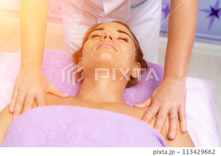 Relaxing massage. European woman getting facial massage in spa salon, side view Relaxing massage. European woman getting facial massage in spa salon, side view 113429662