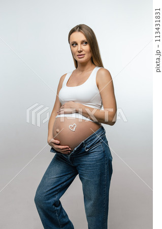 Pregnant woman putting cream on her belly and looking enjoyed Pregnant woman putting cream on her belly and looking enjoyed 113431831