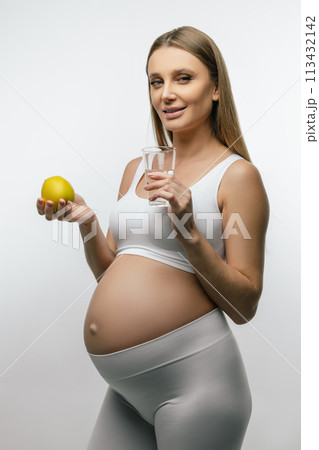 Long-haired young pregnant woman holding fruits in her hands Long-haired young pregnant woman holding fruits in her hands 113432142
