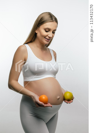 Long-haired young pregnant woman holding fruits in her hands 113432170