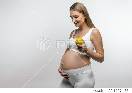 Smiling blonde pregnant woman with apple in hands Smiling blonde pregnant woman with apple in hands 113432178