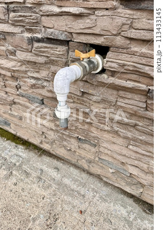 Outdoor faucet water tap with white PVC pipe and reed valve on light brick wall background texture. Copy space, water saving concept 113433145