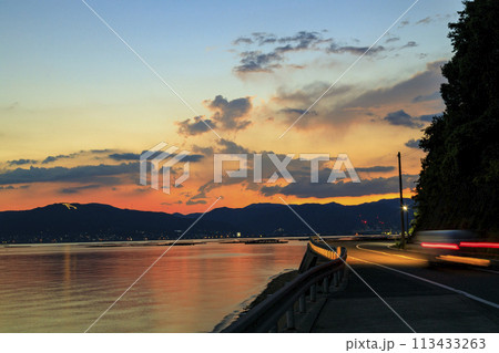 夕焼けの瀬戸内の万葉火と海岸道路 113433263