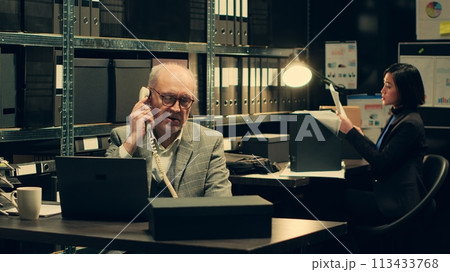 Private investigator requesting crucial information on landline phone call, reaching out to colleagues to find specific evidence relevant to crime case. Detective asks for assistance. Camera A. Private investigator requesting crucial information on landline phone call, reaching out to colleagues to find specific evidence relevant to crime case. Detective asks for assistance. Camera A. 113433768