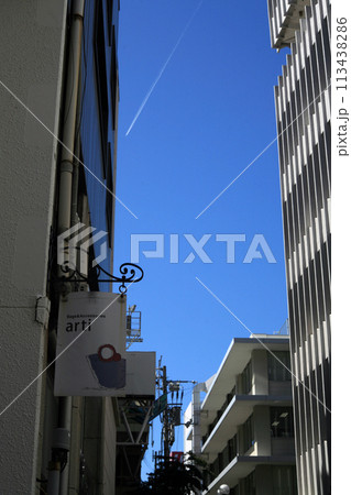 ビル街の店舗看板と飛行機雲 ビル街の店舗看板と飛行機雲 113438286