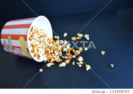 A striped bucket with flying popcorn isolated on a white background. 113438707
