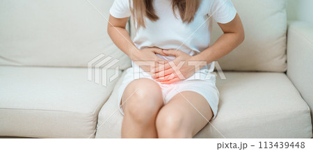 woman having abdomen ache due to Stomach pain, digestion with constipation or Diarrhea from food poisoning, female problem and Endometriosis, Hysterectomy, Stomachache and Menstrual on sofa at home 113439448