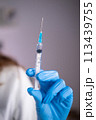 Close-up of a syringe with liquid in the hand of a doctor of a woman in a blue glove 113439755