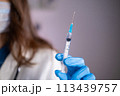 Close-up of a syringe with liquid in the hand of a doctor of a woman in a blue glove 113439757
