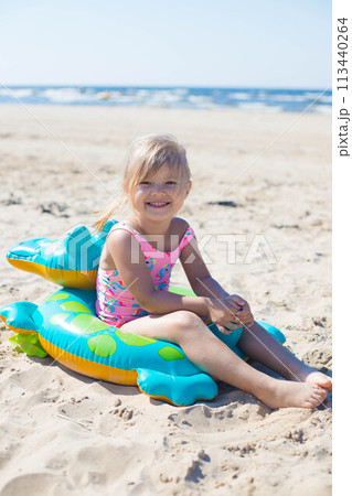 Happy girl sitting and laughing on an inflatable crocodile toy at the beach sunny day Happy girl sitting and laughing on an inflatable crocodile toy at the beach sunny day 113440264