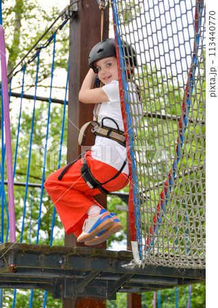 adventure climbing high wire park - people on course in mountain helmet adventure climbing high wire park - people on course in mountain helmet 113440770