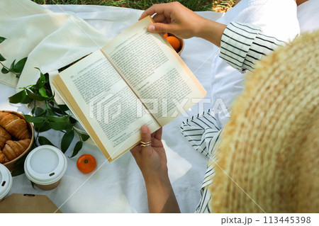 A girl in a straw hat is reading a book on a picnic A girl in a straw hat is reading a book on a picnic 113445398