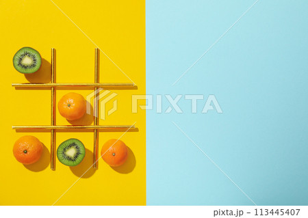 Kiwi, tangerines and straws on yellow and blue background, space for text Kiwi, tangerines and straws on yellow and blue background, space for text 113445407