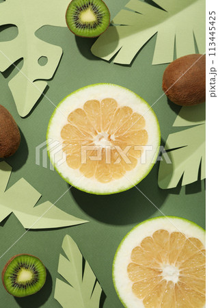 Tropical fruit and paper leaves on green background, top view 113445425