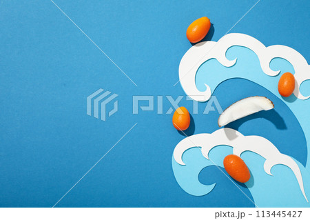 Piece of coconut, whole kumquats and paper waves on blue background, space for text Piece of coconut, whole kumquats and paper waves on blue background, space for text 113445427