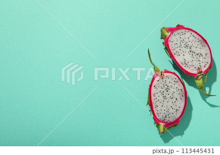 Two half of dragon fruit on blue background, space for text 113445431