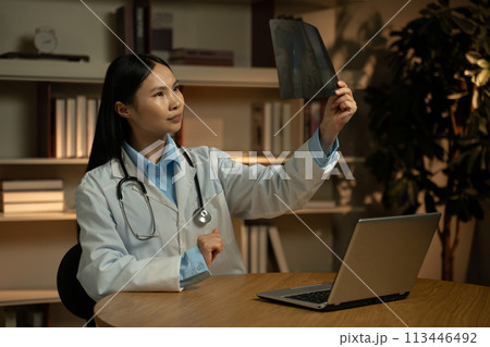 Asian Female Doctor Analyzing X-Ray Results in Medical Office During Evening Hours Asian Female Doctor Analyzing X-Ray Results in Medical Office During Evening Hours 113446492