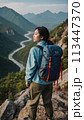 A young happy Chinese young woman with a tourist backpack stands on top of a rock in the mountains, travels and enjoys a beautiful view of the mountains, sky or nature. Untouched nature. Tourism and 113447370