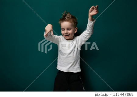 Young Boy Standing in Front of Green Wall 113447869