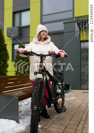 Woman Standing Next to Bike in Front of Building 113448484